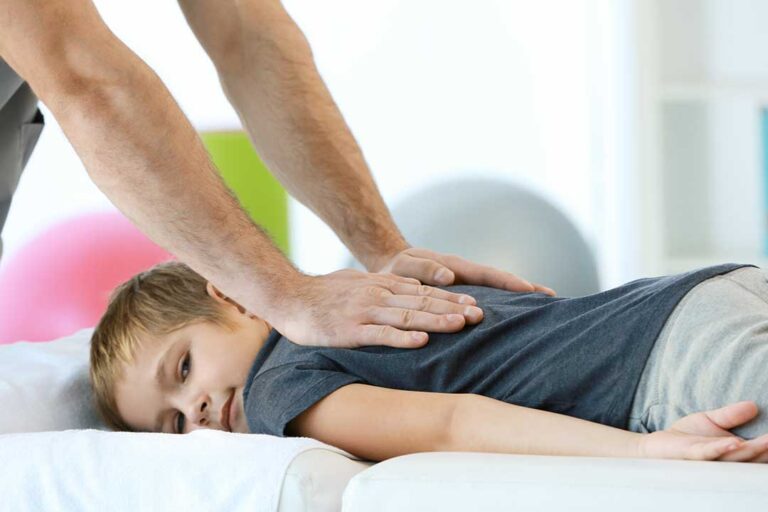 Patient discussing back pain with a chiropractor in an examination room while reviewing health notes.